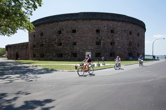 Cyclists riding past Castle Williams on Governors Island on a sunny day